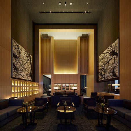 Minimalist Japanese-style lobby with soaring ceiling, dramatic paper lantern, stone walkway and serene indoor garden at Aman Tokyo