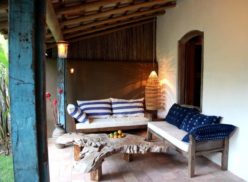 Rustic wooden four-poster bed with white linens in a luxurious Brazilian eco-resort suite, featuring traditional architecture and tropical natural lighting