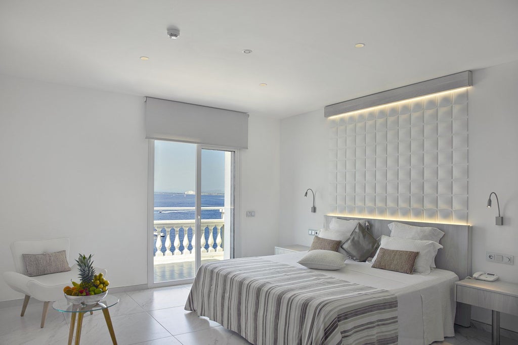 Elegant whitewashed Hotel Vistabella perched on coastal cliffs, featuring Mediterranean architecture and panoramic sea views at sunset