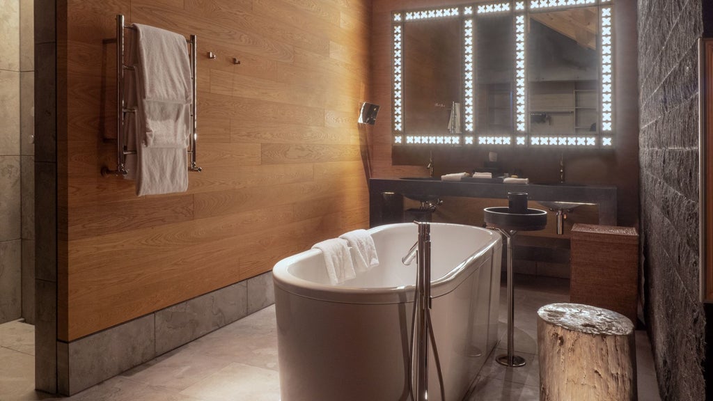 Luxurious alpine suite with panoramic mountain views, minimalist wooden design, soft neutral tones, and floor-to-ceiling windows at The Chedi Andermatt hotel