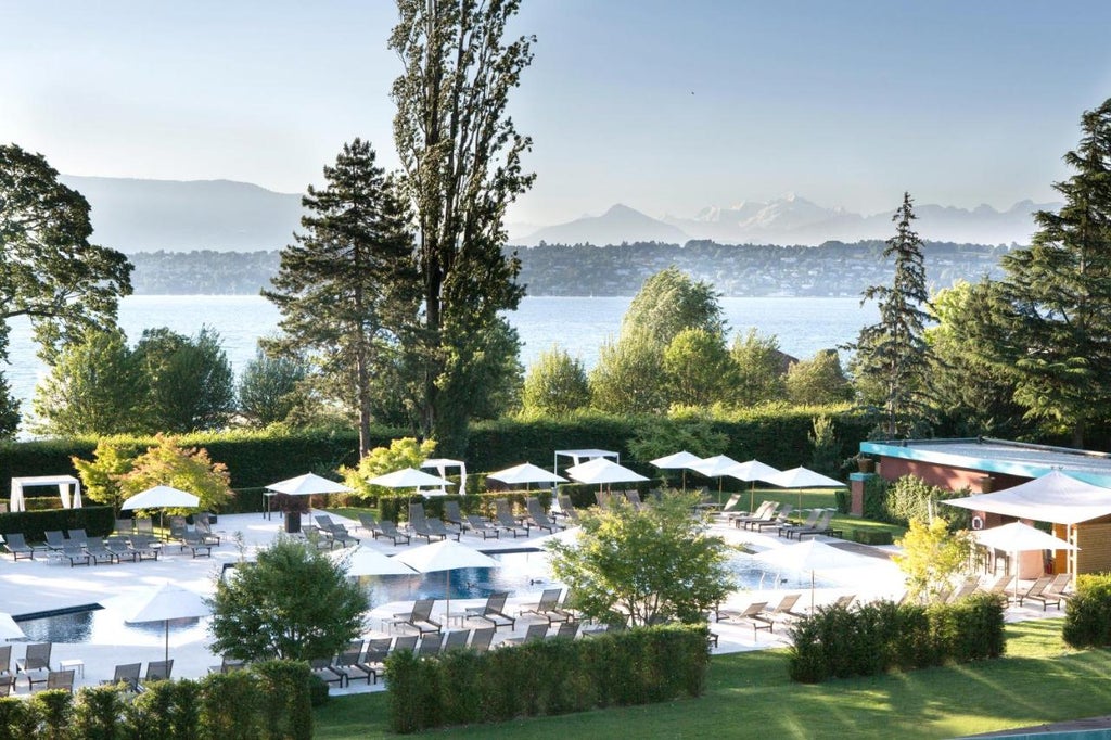 Lakefront luxury hotel in Geneva with Belle Époque architecture, manicured gardens and private dock overlooking Lake Geneva at sunset