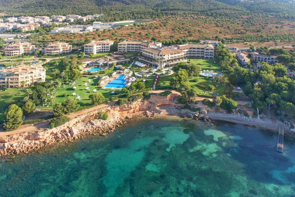 Luxurious Mediterranean resort with elegant white buildings, cascading pools, lush gardens and ocean views along Mallorca's coastline