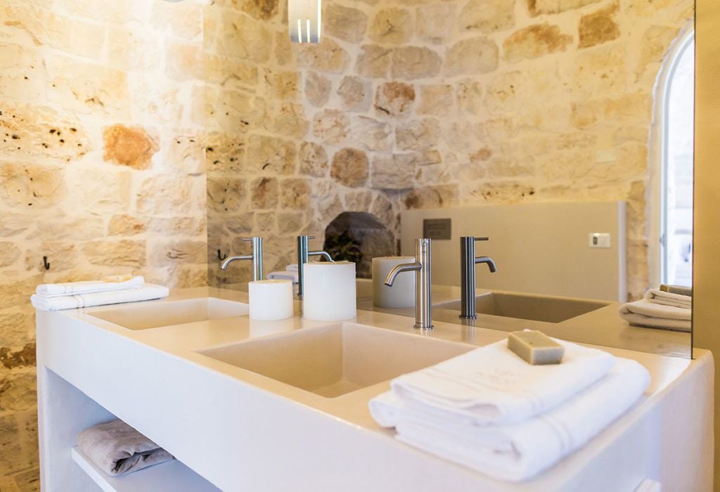 Luxurious stone trulli accommodation in Puglia, Italy, featuring traditional white-domed architecture with elegant rustic interior design and soft lighting.