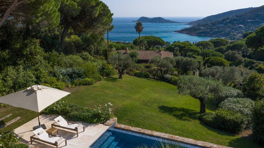 Elegant infinity pool overlooking Mediterranean Sea at sunset, white modern hotel building nestled in lush hillside gardens