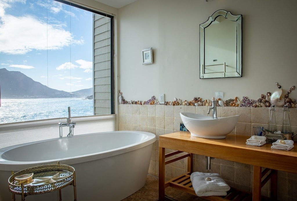 Luxury ocean-front suite with private deck overlooking Chapman's Peak, showcasing elegant furnishings against dramatic mountain backdrop