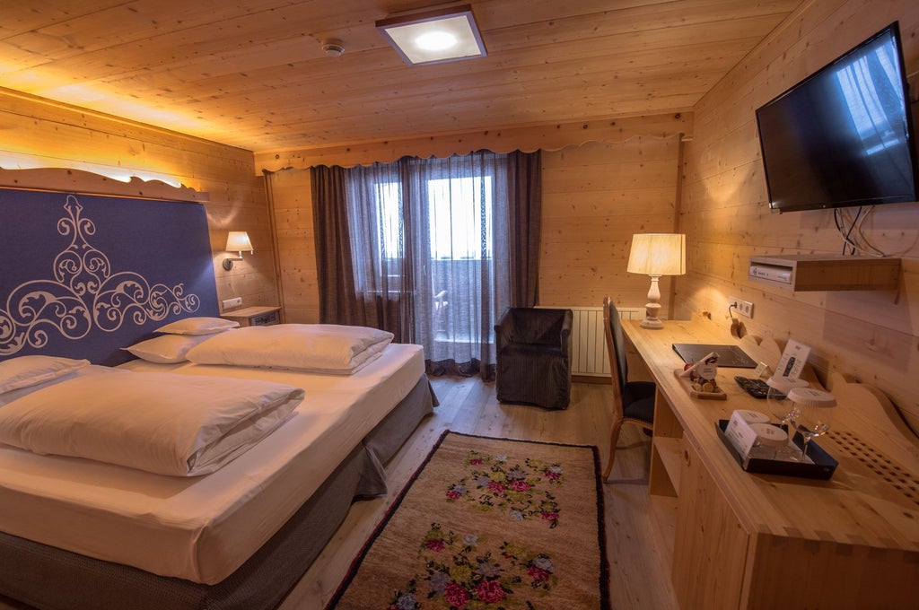 Elegant mountain-view superior room with wooden paneling, king bed, modern lighting, and luxurious furnishings in alpine style