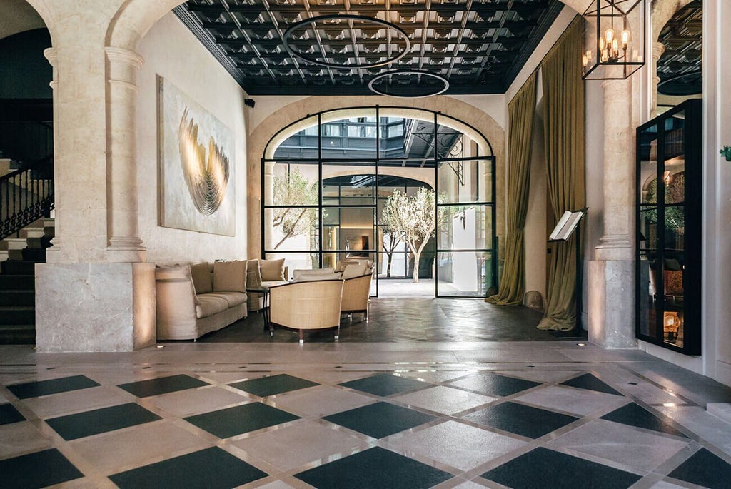 Luxurious boutique hotel in Palma de Mallorca with elegant stone facade, colonial-style architecture, and warm Mediterranean sunlight highlighting historic details