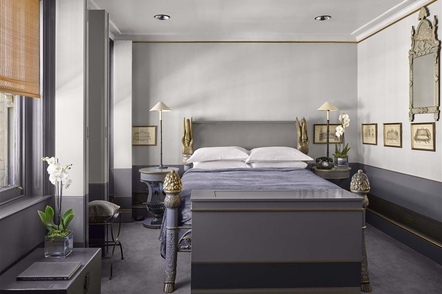 Elegant dark-toned double room with plush velvet headboard, mood lighting, and sophisticated design at luxury boutique hotel in urban setting