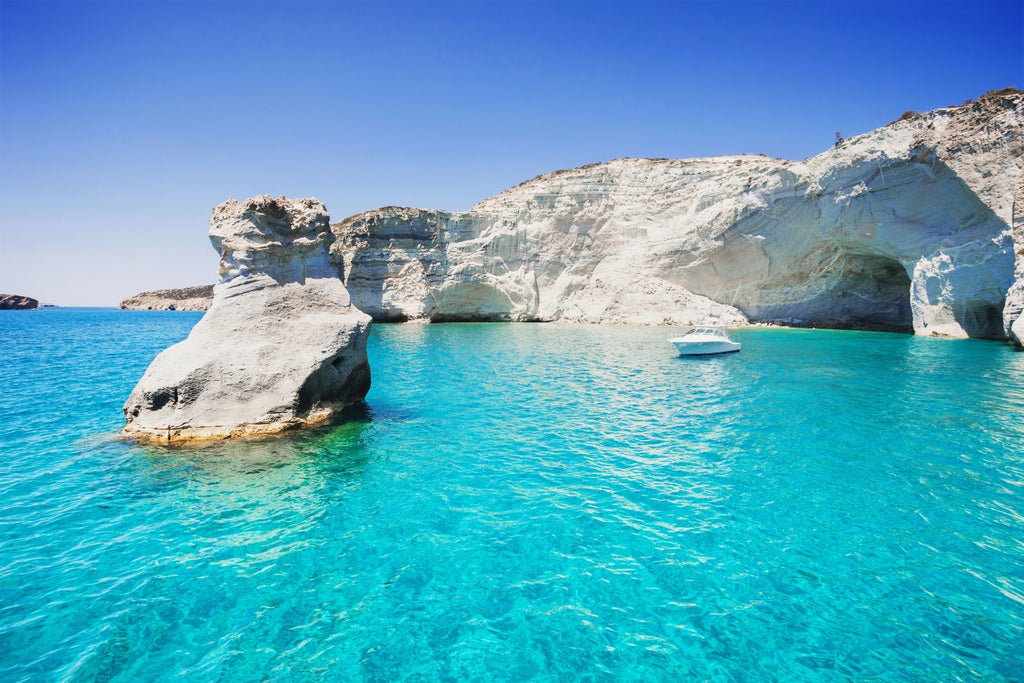 Whitewashed seaside villa overlooking crystal-blue Aegean Sea, nestled in rugged Milos cliffs with infinity pool reflecting sunset hues