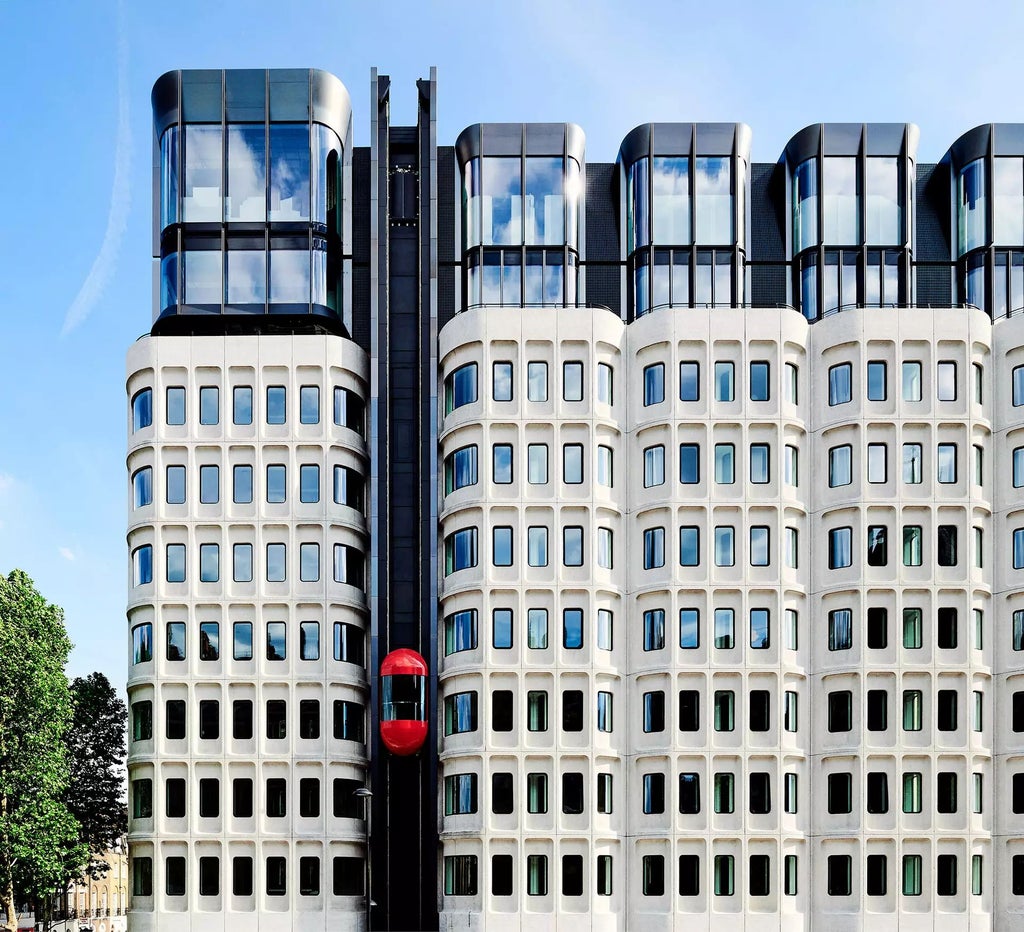 Luxurious rooftop bar at The Standard hotel overlooking London's skyline, featuring modern design with sleek furniture and panoramic urban views at sunset