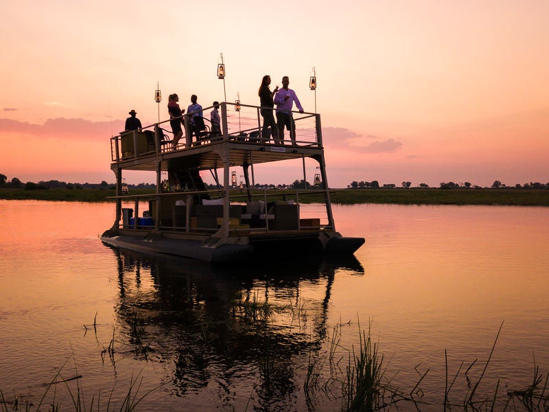 Luxury thatched-roof safari lodge overlooking Linyanti River, with private deck, plunge pool and panoramic wilderness views at sunset