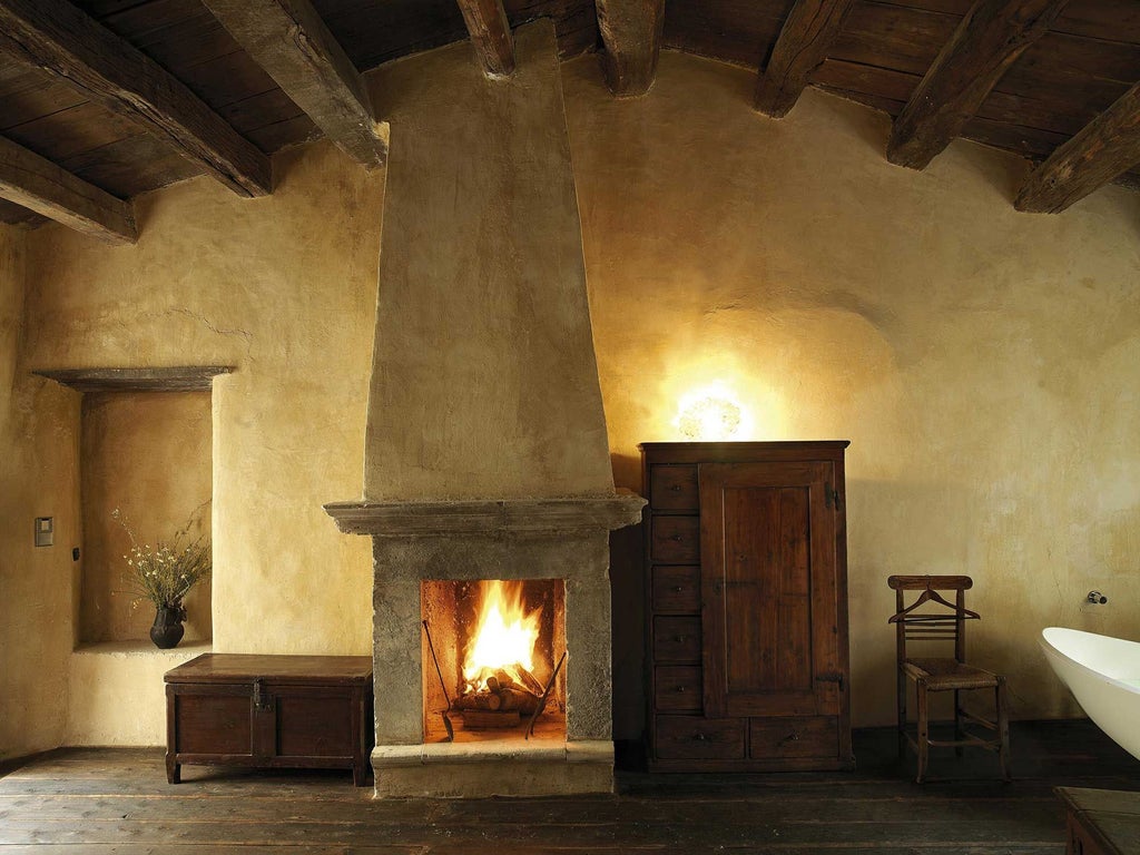 Rustic stone-walled Italian hotel room with antique wooden bed, handcrafted textiles, and soft warm lighting in scenic mountainside accommodation