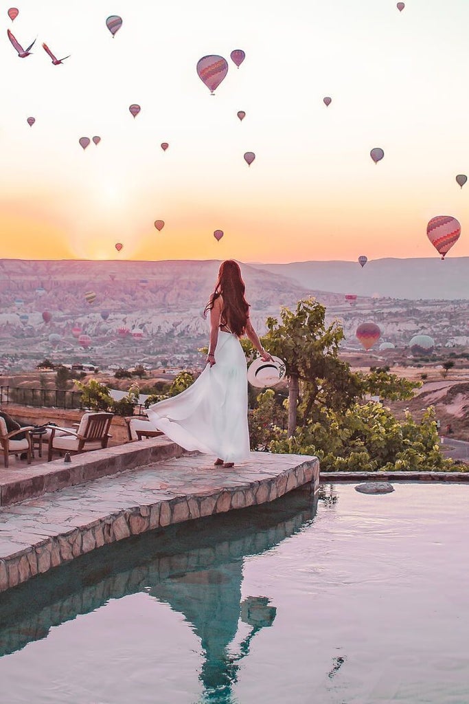 Luxurious boutique Museum Hotel nestled in Cappadocia's rocky landscape, featuring traditional stone architecture and panoramic mountain views at sunset