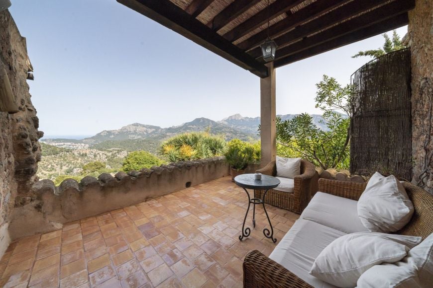 Elegant whitewashed Mallorcan-style deluxe room with rustic wooden furniture, plush white linens, and serene minimalist Mediterranean design