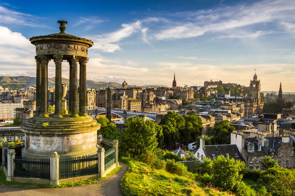 Majestic Edinburgh Castle perched on rocky cliff, historic Old Town skyline with gothic spires and elegant Georgian architecture at golden hour