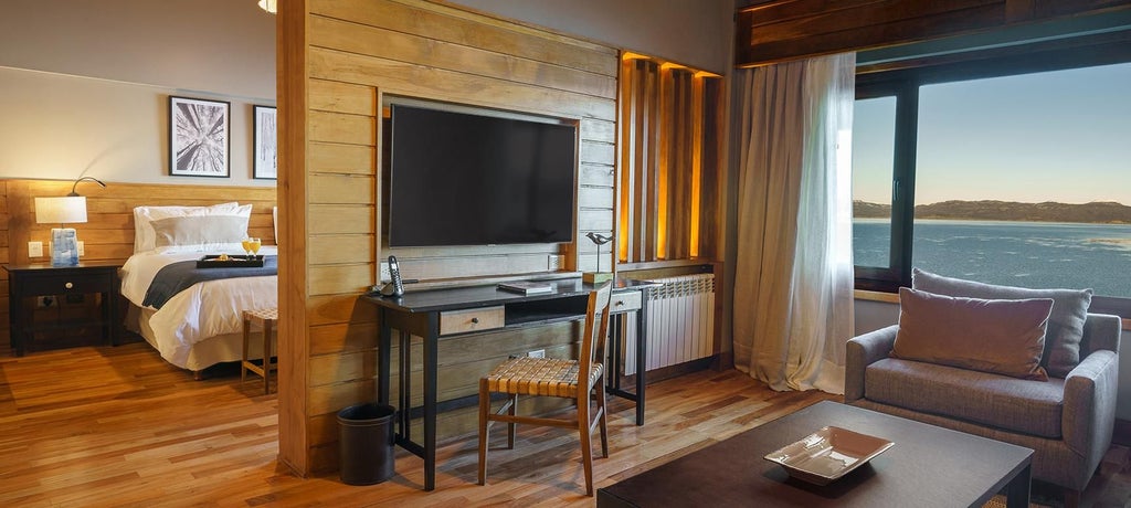 Luxurious Patagonian suite overlooking Beagle Channel, featuring elegant decor, panoramic windows, and tranquil natural landscape with soft, warm lighting