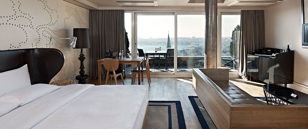 Luxurious king room at Witt Istanbul Hotel with panoramic cityscape, modern decor, floor-to-ceiling windows, and private terrace overlooking urban Turkish landscape