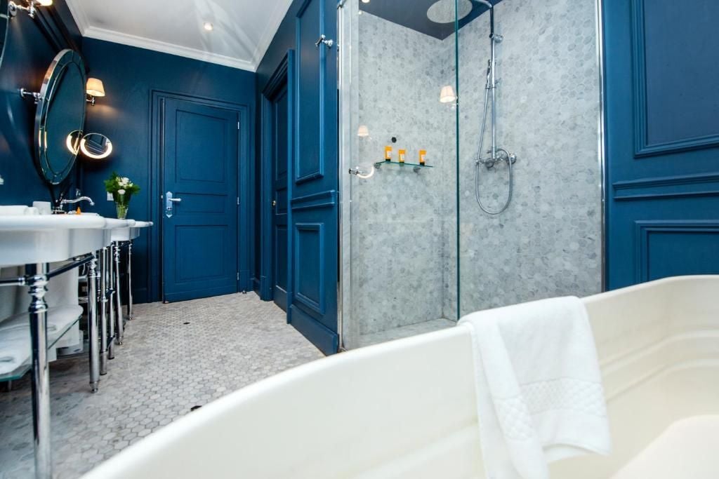 Elegant Dama Suite at Palazzo Dama, featuring plush white bedding, contemporary marble decor, and expansive windows overlooking an Italian cityscape.