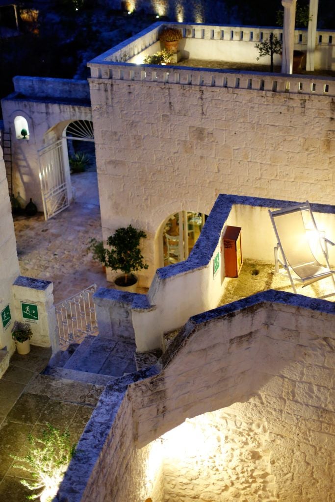 Rustic stone farmhouse hotel nestled in Puglia's countryside, with sun-drenched stone walls, olive trees, and traditional Mediterranean architectural charm