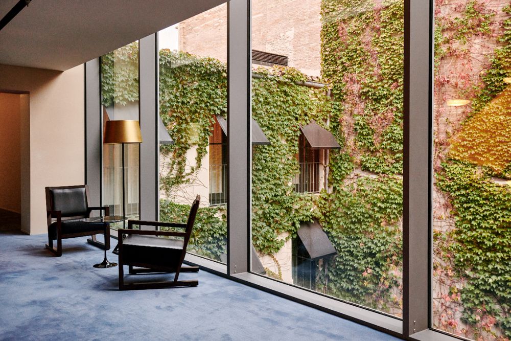 Historic Hotel Mercer, Barcelona, showcasing elegant sandstone facade with ornate arched windows, wrought iron balconies and flowering plants