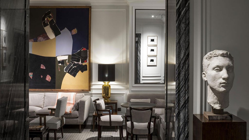 Elegant marble lobby of boutique hotel with plush white armchairs, contemporary chandeliers, and refined Parisian architectural details in soft neutral tones