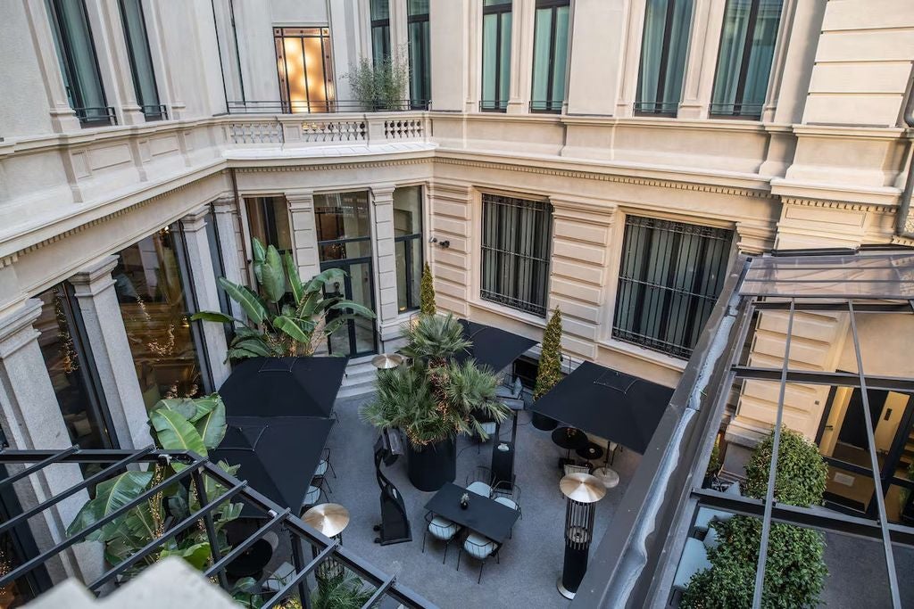 Elegant 1920s art deco façade of Palazzo Touring Club Milan hotel with ornate stone details, arched windows and historic charm.