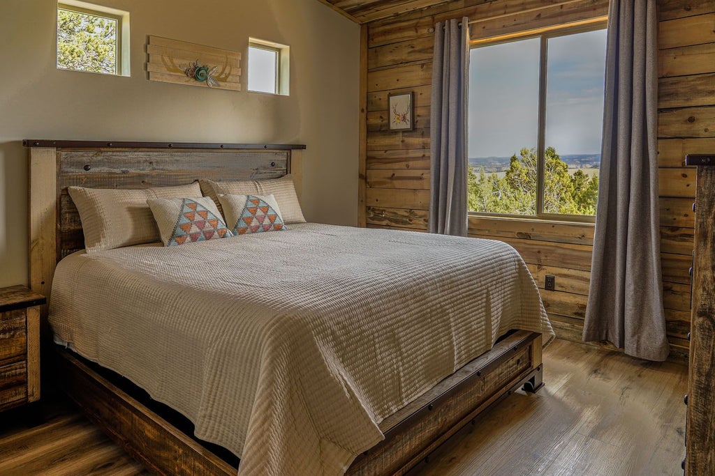 Rustic lodge room with wooden furnishings, plush bedding, and large windows overlooking scenic mountain landscape at scenic Mountain Ranch resort in United States