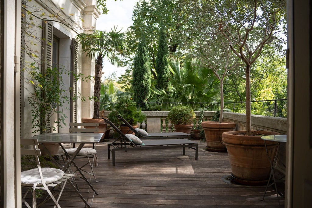 Elegant French boutique hotel exterior with stone facade, wrought-iron balconies, and lush garden terrace in soft afternoon light