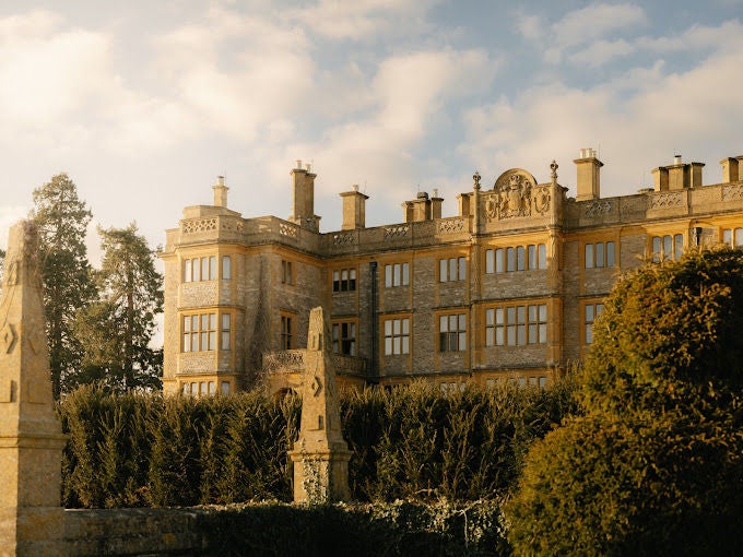 Elegant stone manor hotel with manicured gardens, featuring Georgian architecture, tall windows and a grand entrance framed by ivy