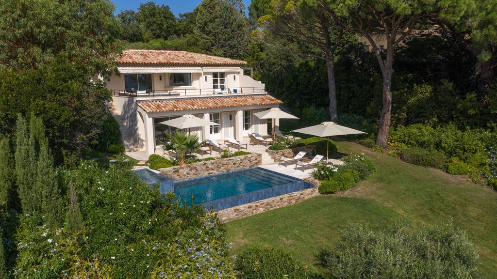 Elegant Mediterranean villa with infinity pool overlooking azure coastline, white modern architecture nestled among manicured gardens