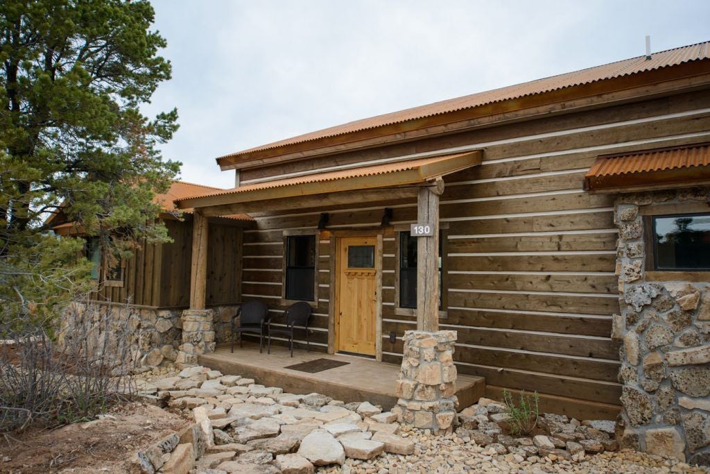 Rustic wooden lodge bedroom with plush bedding, panoramic mountain views, warm earth tones, and elegant wilderness-inspired interior design at scenic ranch retreat.