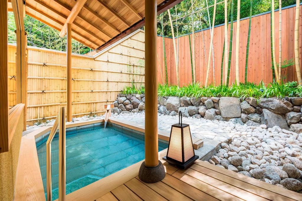 Japanese luxury ryokan with traditional wooden architecture, zen garden, and mountain views, nestled among lush autumn foliage