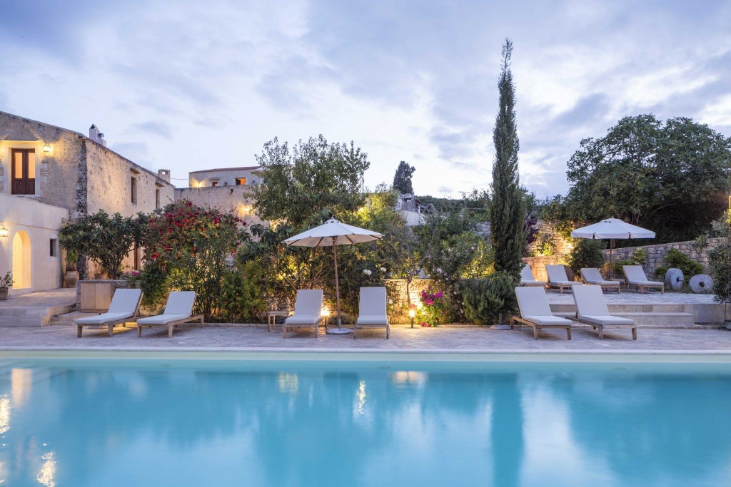 Elegant stone cottage in traditional Greek village setting surrounded by olive groves, featuring rustic architecture and luxury details