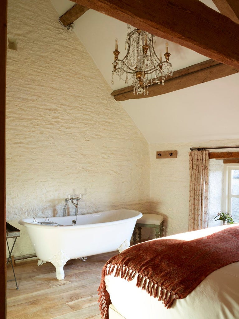 Elegant thyme-themed cottage suite with plush cream armchair, soft textured throws, and rustic wooden furniture in a warm, inviting UK retreat