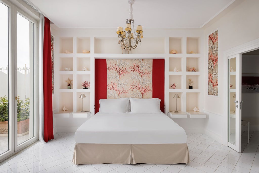 Luxurious coral-toned suite with panoramic Mediterranean views, elegant maritime-inspired decor, plush furnishings, and sweeping coastal landscape at Bellevue Syrene in Italy