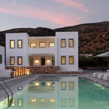 Luxurious white-washed Cycladic hotel overlooking azure Aegean Sea, featuring minimalist architecture and infinity pool with sweeping panoramic island views