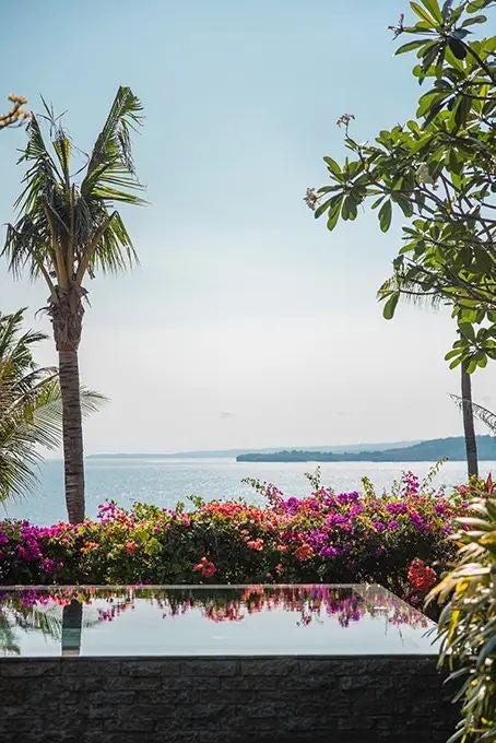 Luxurious open-air villa overlooking lush Indonesian landscape, featuring elegant four-poster bed and panoramic view of tropical scenery at NIHI Sumba resort