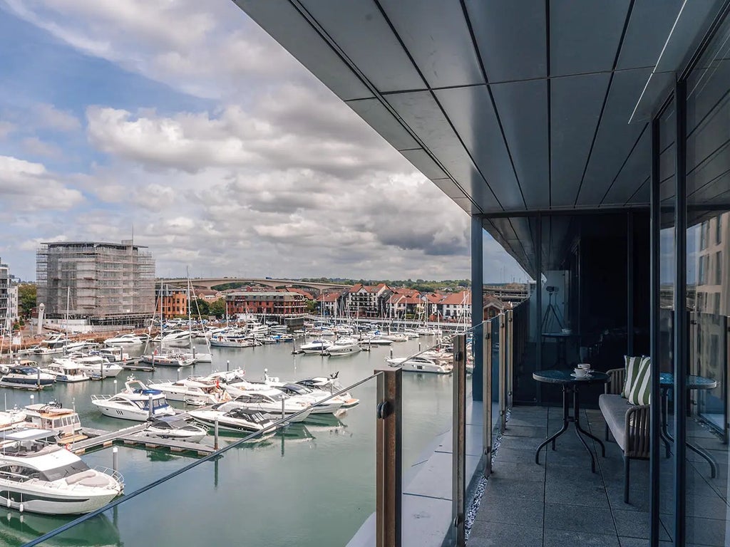 Spacious Marina View Suite with private balcony overlooking Southampton's harbor, featuring modern furnishings and elegant maritime-inspired design