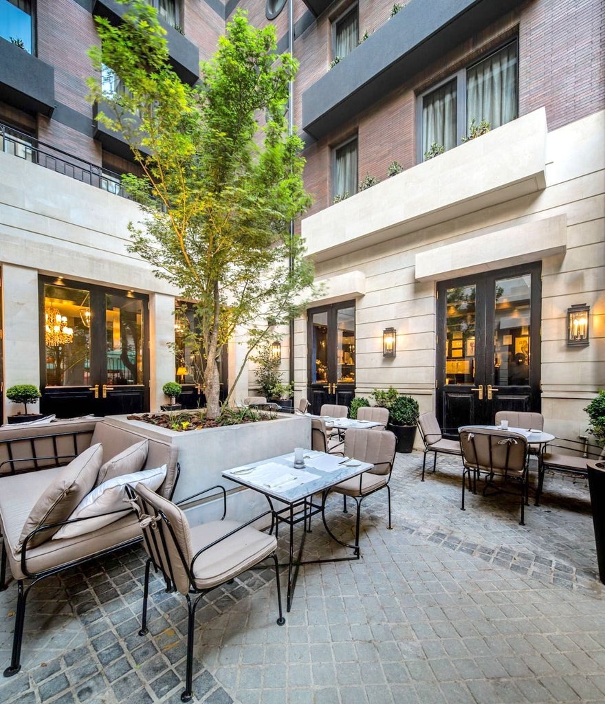 Modern luxury hotel exterior with neoclassical architecture featuring glass windows, ornate stonework and elegant balconies in Santiago