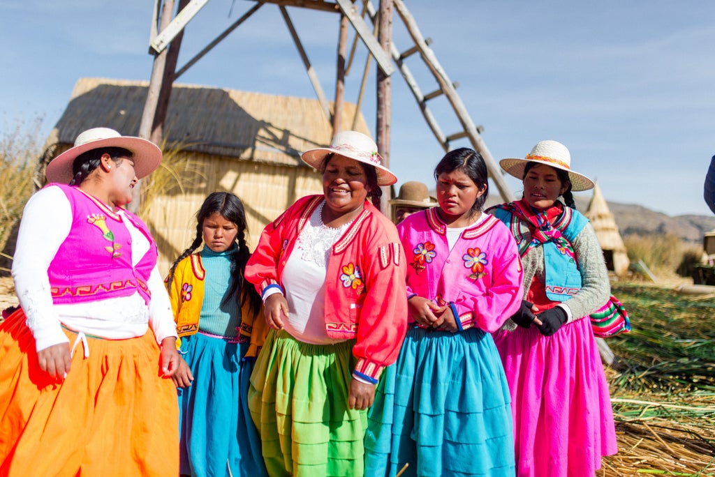 Luxurious lakefront lodge with stone facade and floor-to-ceiling windows overlooking Lake Titicaca's tranquil waters at sunset