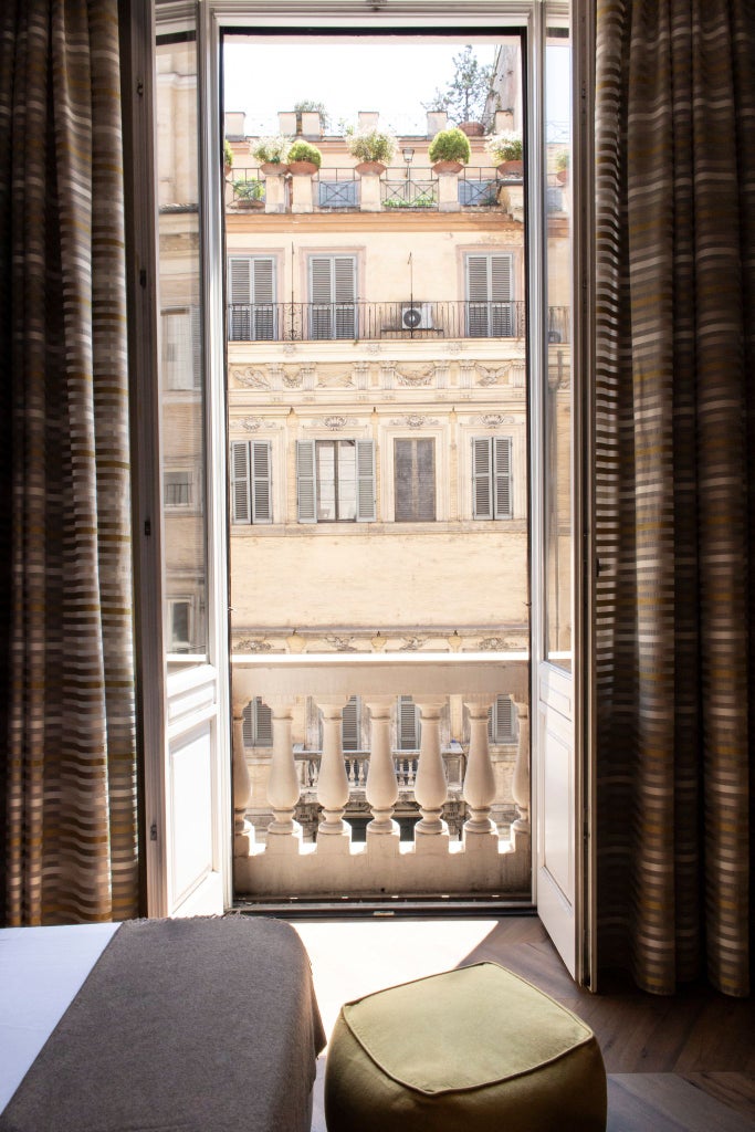 Elegant Italian luxury suite with rich cream walls, ornate chandelier, plush white bedding, and classic wooden furnishings in warm, inviting tones