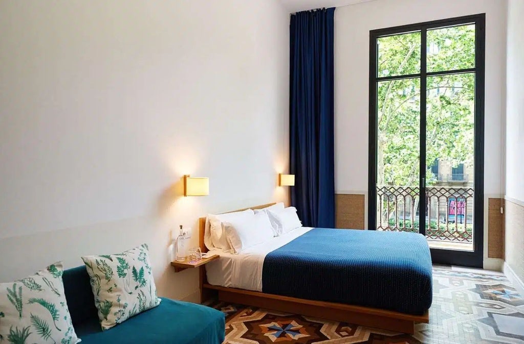 Spacious sunlit hotel room with minimalist design, white linens, large windows overlooking Gran Via, Barcelona, featuring modern furniture and elegant decor