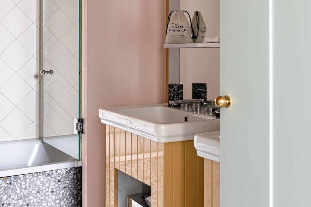 Elegant single hotel room with Venetian-inspired decor, featuring soft cream walls, antique wood furnishings, and large arched window overlooking canal