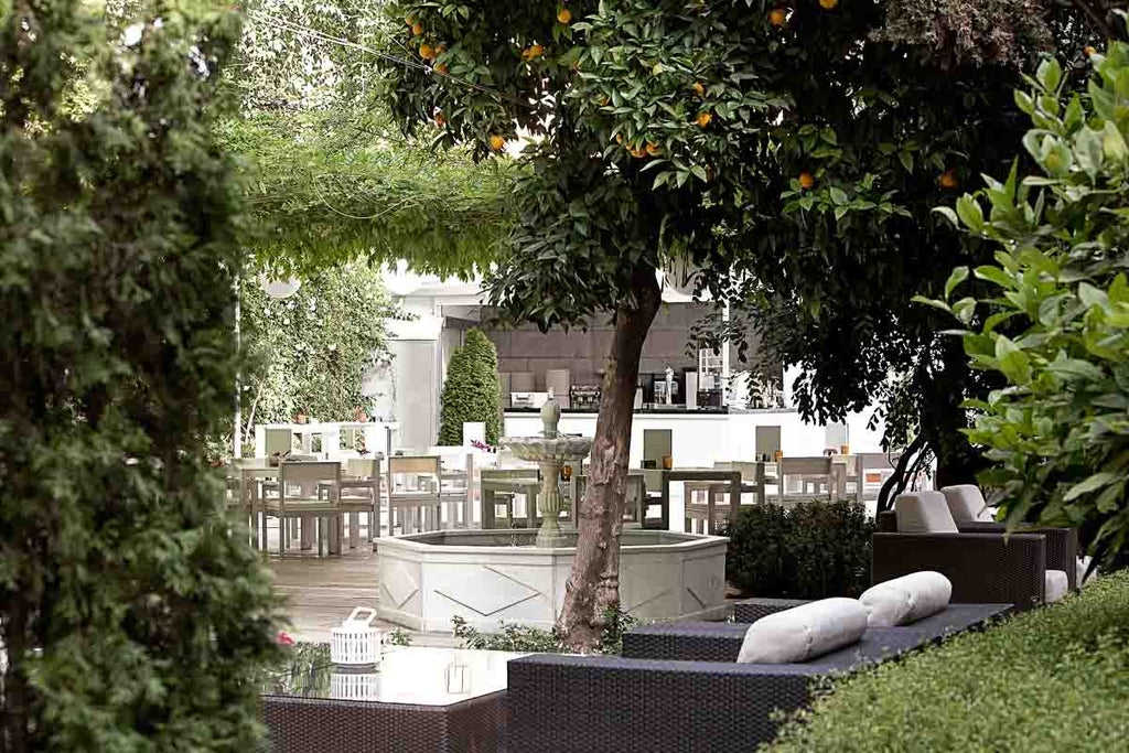 Elegant 19th-century palace hotel with white stone facade, ornate balconies, and manicured gardens in Granada's historic center