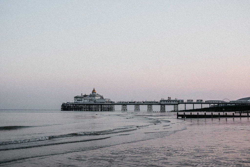 Luxurious seaside hotel with modern glass facade, overlooking calm coastal waters, featuring sleek architectural design and panoramic ocean views at sunset