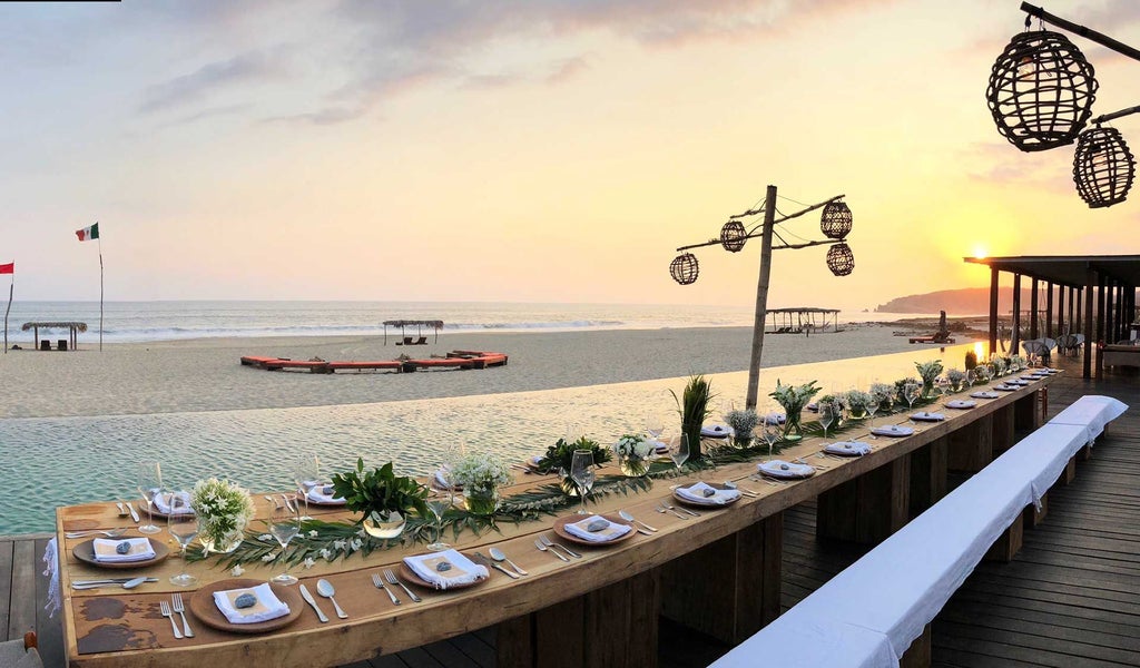 Minimalist beachfront hotel with white-washed architecture, infinity pool overlooking Pacific Ocean, tropical palms, and modern Mexican design aesthetic