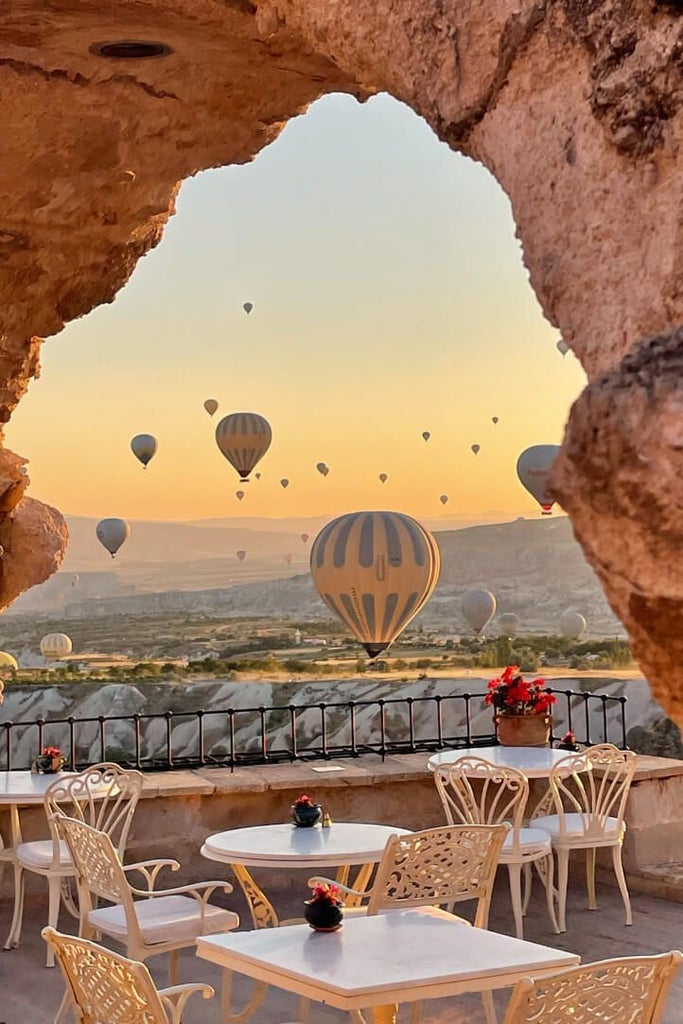 Luxurious boutique hotel with stone architecture nestled in Cappadocia, featuring carved rooms, panoramic views of unique volcanic landscape at sunset