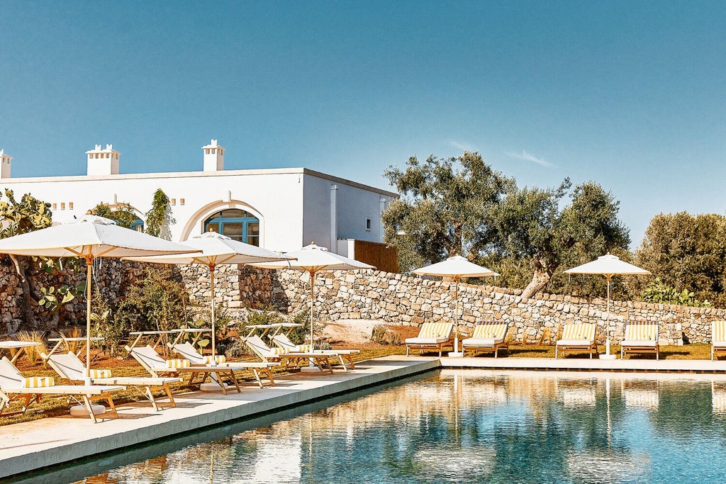 Rustic luxe stone villa nestled in golden Italian countryside, featuring white-washed walls, elegant terrace, and panoramic views of rolling Puglia landscape