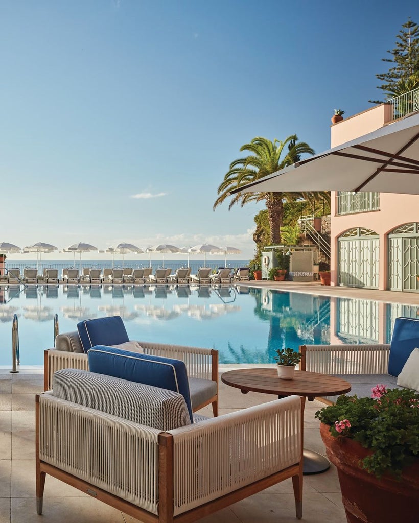 Historic pink luxury hotel Belmond Reid's Palace perched on clifftop with lush gardens, overlooking Atlantic Ocean in Madeira, Portugal