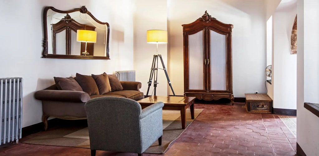 Elegant Spanish colonial-style bedroom with stone walls, antique wooden furniture, soft lighting, and rustic traditional architectural details at Cortijo del Marqués